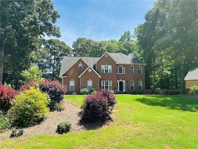 Colonial house featuring a chimney and brick siding