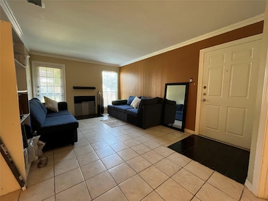 Living area with light tile patterned flooring, ornamental molding, and a fireplace