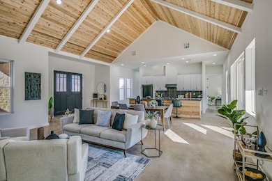 Living area with a wood ceiling with exposed beams, high vaulted ceiling, concrete flooring, and recessed lighting