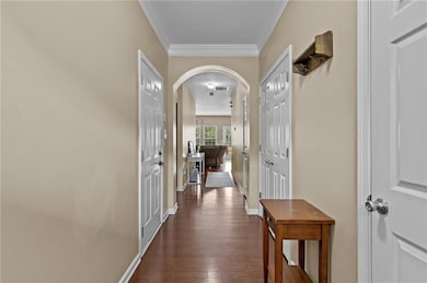 Hall with arched walkways, ornamental molding, and dark wood-style floors