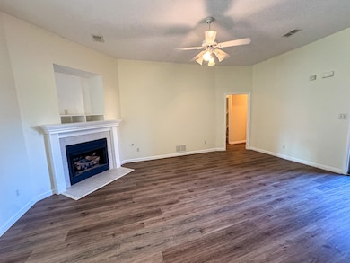 Unfurnished living room with a tile fireplace, a textured ceiling, ceiling fan, and wood finished floors