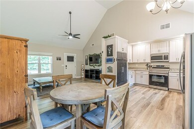 Dining area featuring high vaulted ceiling, light wood-type flooring, a ceiling fan, and a chandelier