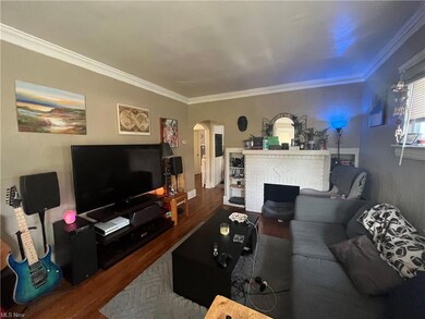 Living room featuring ornamental molding, light hardwood floors, and a fireplace