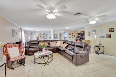 Living room featuring ceiling fan, ornamental molding, and light tile patterned floors