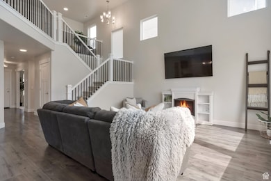Living room with stairway, wood finished floors, baseboards, and a warm lit fireplace