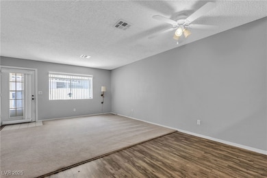 Empty room with wood finished floors, a textured c