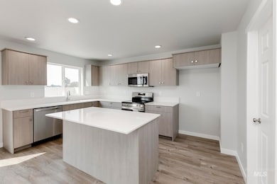 Kitchen with stainless steel appliances, light brown cabinetry, a center island, light wood-type flooring, and recessed lighting