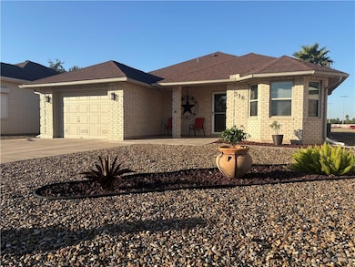 Ranch-style house featuring driveway, a garage, a shingled roof, a patio area, and brick siding
