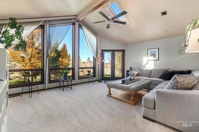 Living room with beam ceiling, light colored carpet, high vaulted ceiling, a skylight, and a ceiling fan