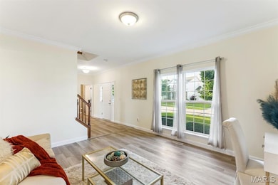Living room with crown molding, light wood-type flooring, and stairs
