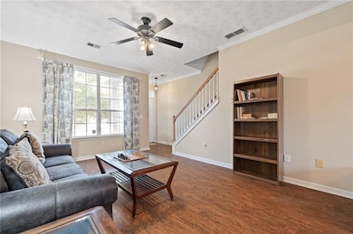 Living room featuring stairs, a ceiling fan, dark 