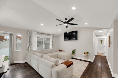 Living area featuring vaulted ceiling, dark wood-style floors, recessed lighting, and ceiling fan