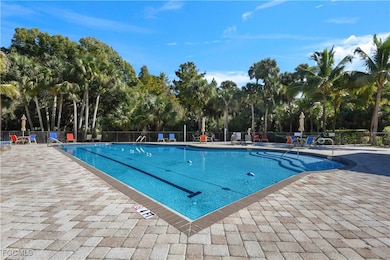 Community pool featuring a patio area and view of wooded area