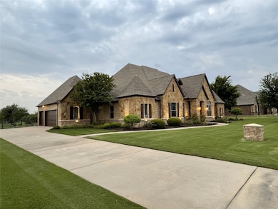 French country home with stone siding, a front yard, driveway, and roof with shingles