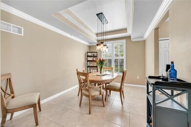 Dining room with a raised ceiling, crown molding, baseboards, a chandelier, and light tile patterned flooring