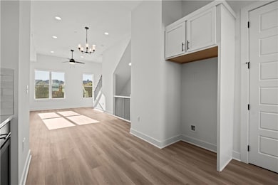 Unfurnished living room with light hardwood / wood-style flooring and ceiling fan with notable chandelier