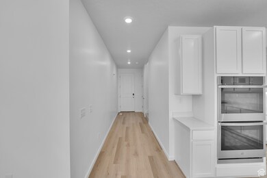 Corridor featuring light wood-style floors and recessed lighting