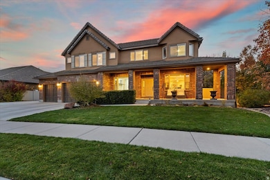 View of front of property with covered porch, stucco siding, a front lawn, concrete driveway, and brick siding