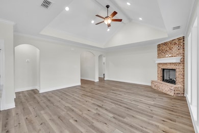 Unfurnished living room with arched walkways, ceiling fan, a fireplace, wood finished floors, and beamed ceiling