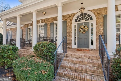 Charming brick front porch with stately columns, updated lighting, and a warm, inviting entryway.