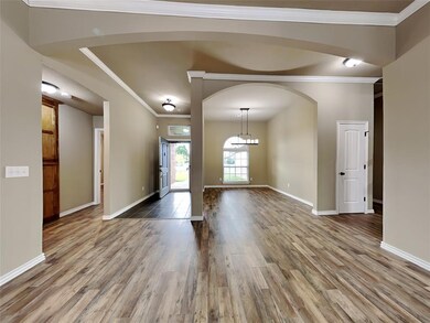Foyer with wood finished floors, arched walkways, and ornamental molding
