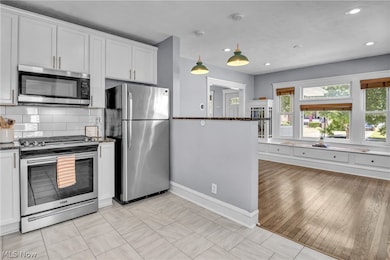 Kitchen featuring appliances with stainless steel finishes, pendant lighting, white cabinets, and light tile patterned floors