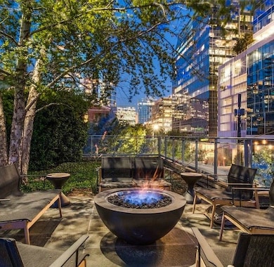 Patio at night with a fire pit, a view of city lights, and a patio area
