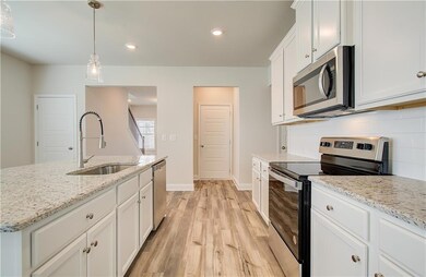 Kitchen featuring stainless steel appliances, white cabinetry, decorative light fixtures, light wood-style flooring, and recessed lighting