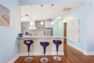 Kitchen featuring freestanding refrigerator, tasteful backsplash, a peninsula, a kitchen breakfast bar, and white cabinets
