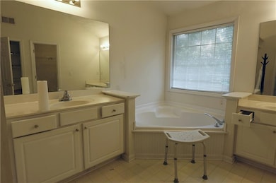 Bathroom with a sink, two vanities, a garden tub, 
