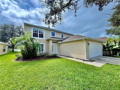 Traditional-style home featuring an attached garage, concrete driveway, a front lawn, and stucco siding