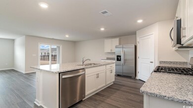 Kitchen with white cabinetry, an island with sink,