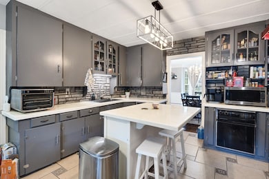 Kitchen with stainless steel microwave, oven, a sink, light countertops, and tasteful backsplash