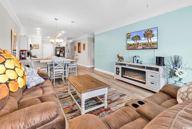 Living area featuring a chandelier, ornamental molding, light wood-type flooring, recessed lighting, and a glass covered fireplace