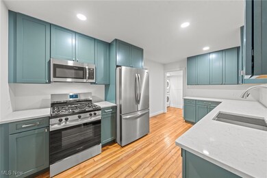 Kitchen with stainless steel appliances, stacked washer / dryer, light hardwood / wood-style floors, and sink