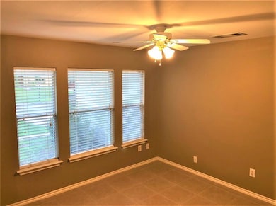 Tiled spare room with a ceiling fan and baseboards