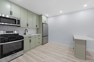 Kitchen featuring appliances with stainless steel finishes, green cabinetry, light wood-style floors, and recessed lighting