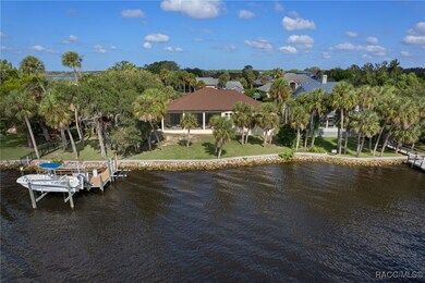 Backside of Home with view of backyard, seawall, dock and boat lift