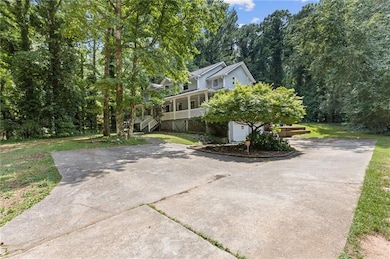 View of front of property with concrete driveway, covered porch, a front lawn, and stairway