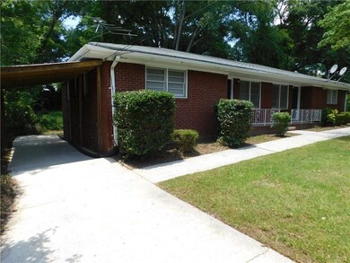Single story home with brick siding, a porch, concrete driveway, and a front yard