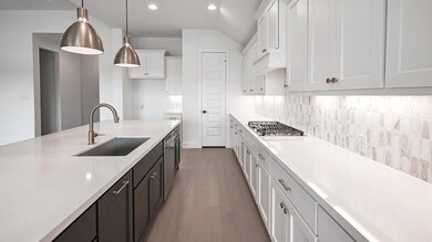 Kitchen featuring a sink, white cabinetry, light 