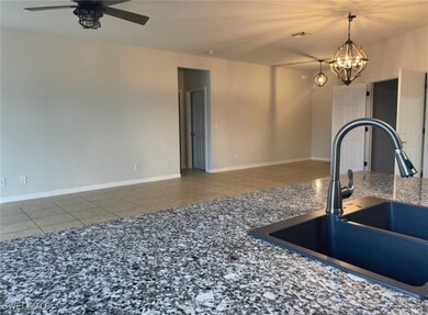 Kitchen with ceiling fan with notable chandelier, sink, and tile patterned floors