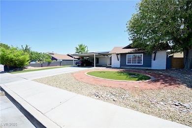 Single story home featuring driveway, an attached carport, and brick siding