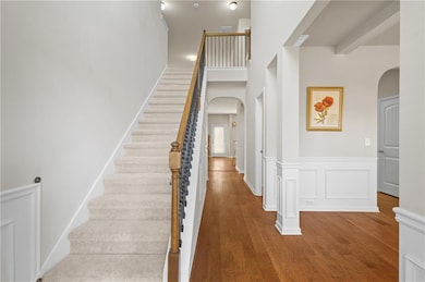 Entryway with arched walkways, wood finished floors, stairway, and a decorative wall