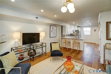 Living area with recessed lighting, ornamental molding, and light wood-style flooring