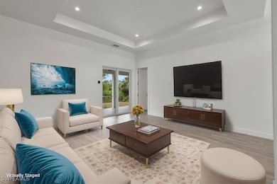 Living room featuring wood finished floors, a raised ceiling, recessed lighting, and baseboards