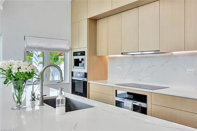 Kitchen featuring tasteful backsplash, black appliances, modern cabinets, and a sink