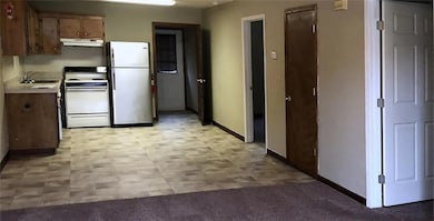 Kitchen featuring freestanding refrigerator, white electric stove, light countertops, under cabinet range hood, and light flooring