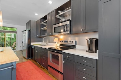 Kitchen featuring appliances with stainless steel finishes, open shelves, light wood-style floors, recessed lighting, and wood counters