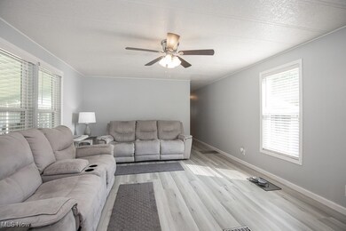 Living area featuring healthy amount of natural light, a ceiling fan, and light wood finished floors